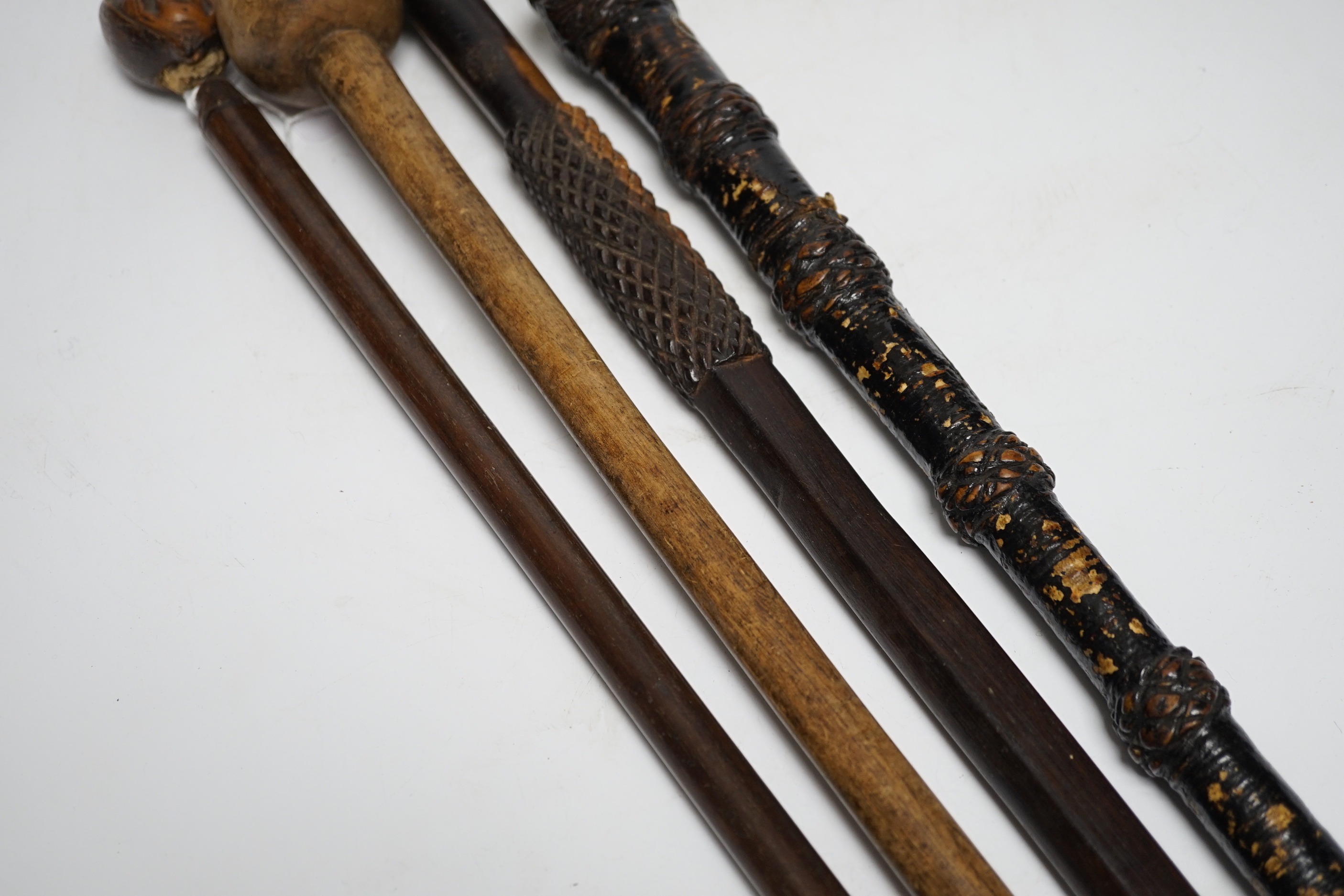 A ceremonial sword stick with removable brush end, a 19th century continental carved head with glass eyes on associated cane stick and two others, longest 93cm